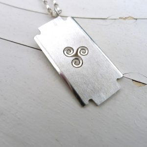 The minimalist design of the razor pendant represents simplicity and understated elegance, reflecting the wearer's preference for a clean, uncluttered look. The spiral symbol can be interpreted as representing spiritual growth The minimalist design of the razor pendant represents simplicity and understated elegance, reflecting the wearer's preference for a clean, uncluttered look. The spiral symbol can be interpreted as representing spiritual growth