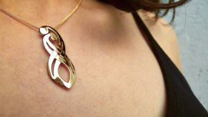 Crafted in rich 18ct yellow gold this Mothers necklace represents the lifelong bond between mother and child. Look closely as they embrace, the arms entwine and turn into the symbol infinity